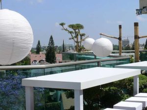 ריהוט דקורטיבי להשכרה- שולחנות וכיסאות בר לבנים עם פנסי תאורה תלויים ועמודי במבוק דקורטיביים