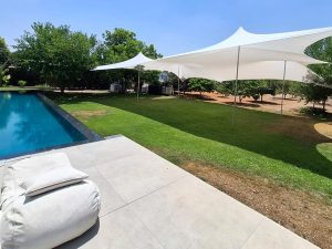 פרגולת בד מתוחה ליד בריכה ביתית עם ריהוט חוץ מודרני